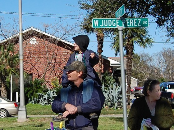 Dad with kid on his shoulders waits for parade to pass