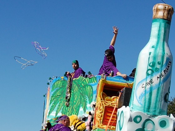 Float featuring giant bottle figurehead and showboating krewe riders