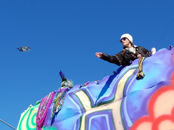 Lady rider tosses beads from upper float deck